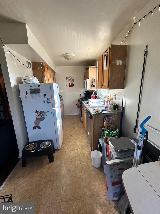 kitchen with white refrigerator, range, and light tile patterned floors