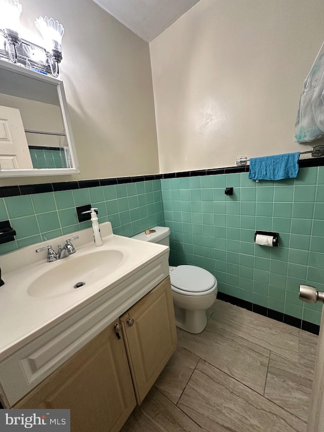 bathroom featuring vanity, tile walls, and toilet