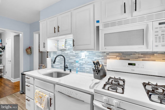 kitchen with sink, white appliances, white cabinetry, backsplash, and light wood-type flooring