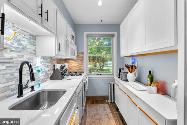 kitchen featuring sink, white appliances, radiator heating unit, white cabinets, and decorative backsplash