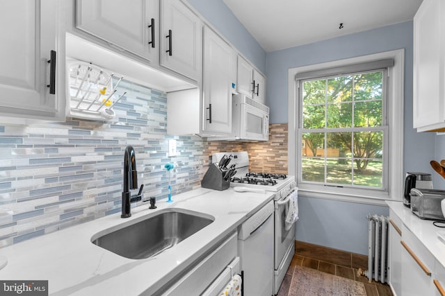 kitchen with white cabinetry, sink, backsplash, and white appliances