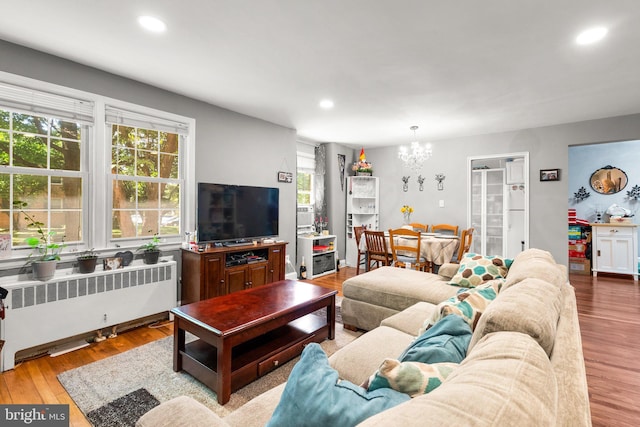 living room featuring radiator, light hardwood / wood-style floors, and a chandelier