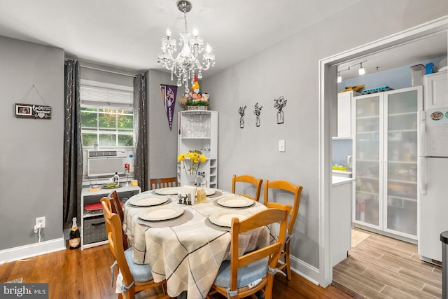 dining room featuring cooling unit, hardwood / wood-style floors, and a notable chandelier