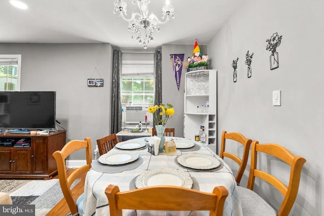 dining room with an inviting chandelier, cooling unit, a wealth of natural light, and light hardwood / wood-style flooring