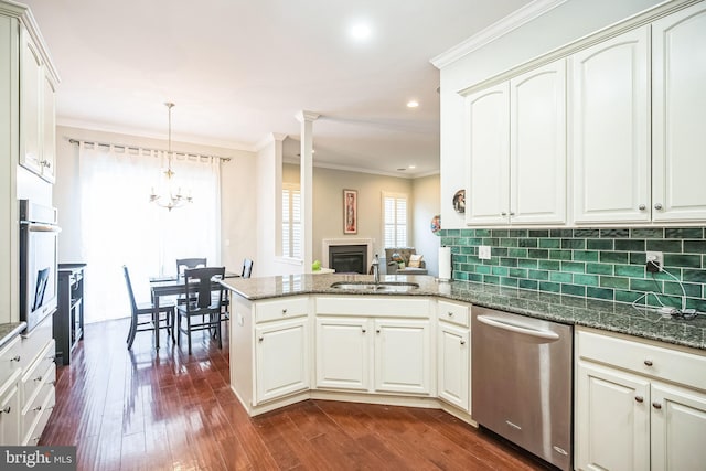 kitchen with a chandelier, appliances with stainless steel finishes, kitchen peninsula, pendant lighting, and sink