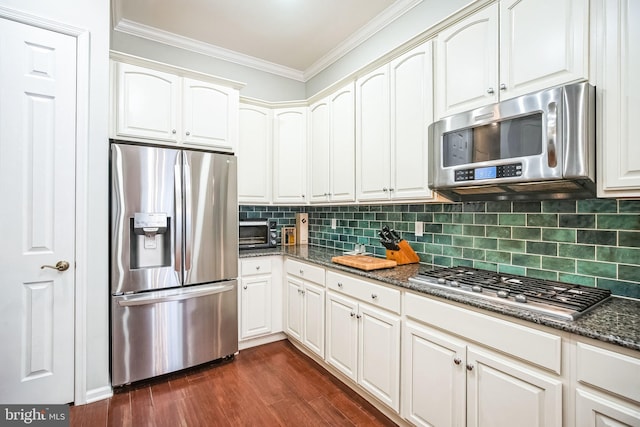 kitchen with white cabinets, dark stone countertops, decorative backsplash, dark hardwood / wood-style floors, and appliances with stainless steel finishes