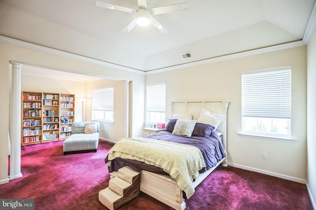 carpeted bedroom featuring a raised ceiling, ceiling fan, multiple windows, and decorative columns