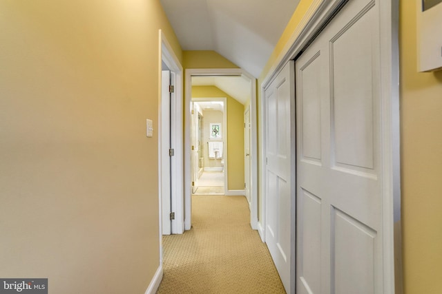 hallway with lofted ceiling and light carpet