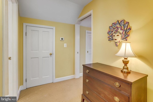 hallway featuring lofted ceiling and light colored carpet