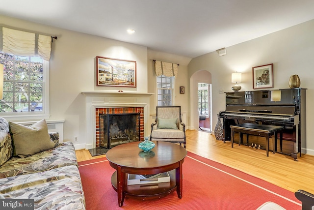 living room with hardwood / wood-style flooring, a tile fireplace, and a healthy amount of sunlight