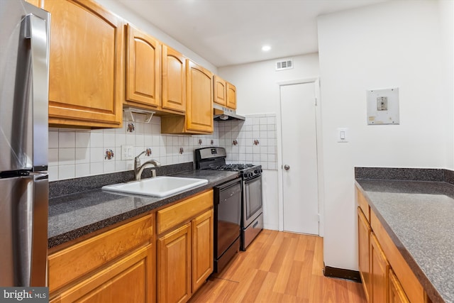 kitchen featuring tasteful backsplash, sink, stainless steel appliances, and light hardwood / wood-style floors