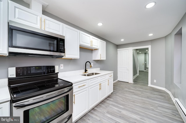 kitchen with sink, baseboard heating, appliances with stainless steel finishes, light hardwood / wood-style floors, and white cabinetry