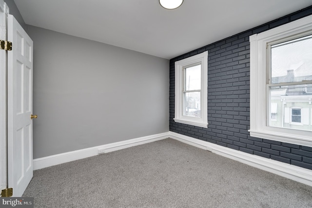 unfurnished room with carpet floors and brick wall