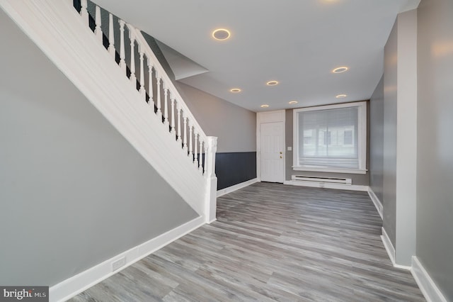 foyer entrance featuring wood-type flooring and a baseboard heating unit