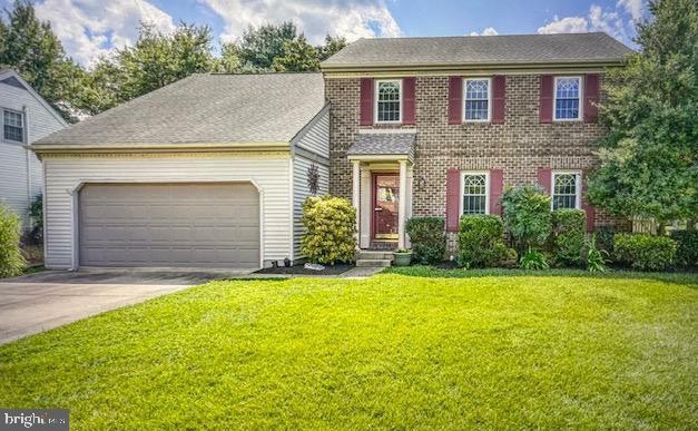 colonial inspired home featuring a garage and a front lawn