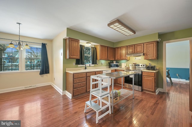 kitchen featuring dark wood-type flooring, sink, pendant lighting, and stainless steel appliances