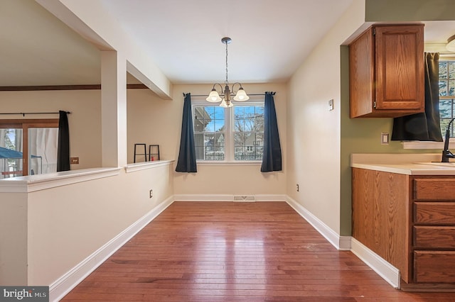 unfurnished dining area with sink, an inviting chandelier, and dark hardwood / wood-style floors