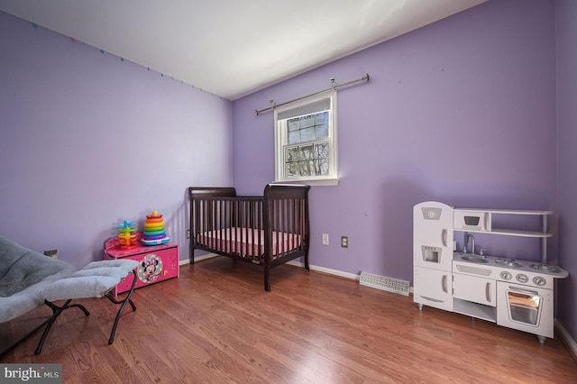 bedroom featuring a crib and hardwood / wood-style flooring