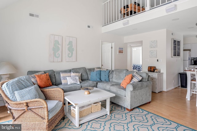 living room with a towering ceiling and light hardwood / wood-style floors