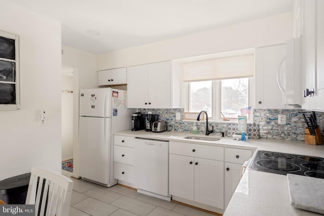 kitchen featuring light tile patterned floors, decorative backsplash, white appliances, white cabinets, and sink