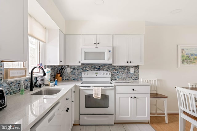 kitchen with light stone countertops, sink, white cabinets, and white appliances