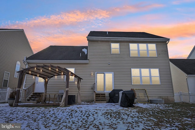 snow covered rear of property with a pergola