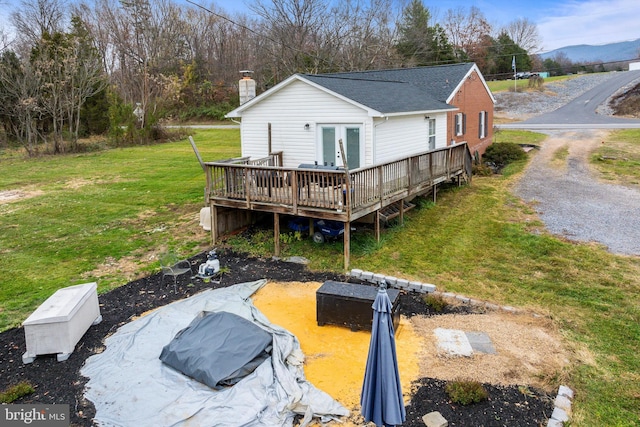 rear view of house with french doors, a deck, and a lawn