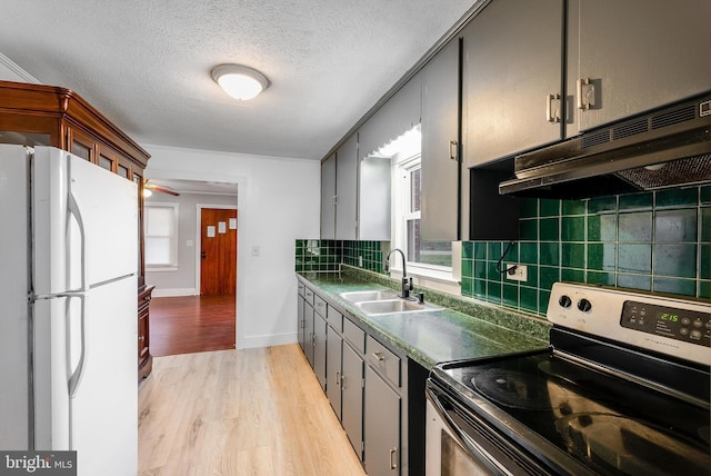 kitchen with sink, tasteful backsplash, white refrigerator, light hardwood / wood-style floors, and stainless steel range with electric stovetop