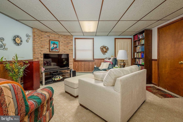 carpeted living room with a paneled ceiling and wood walls