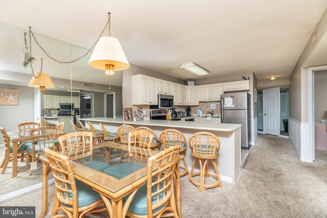 carpeted dining room with sink and a textured ceiling