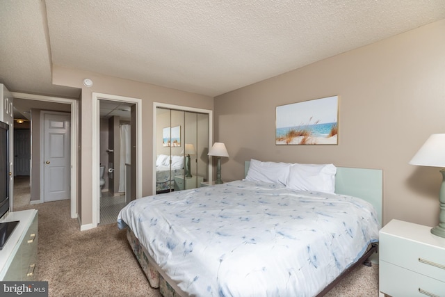 bedroom with a textured ceiling, light colored carpet, and a closet