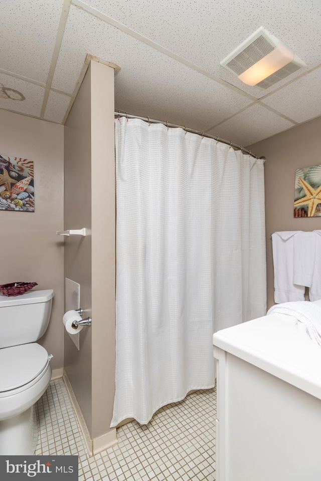 bathroom featuring tile patterned flooring, a paneled ceiling, and toilet