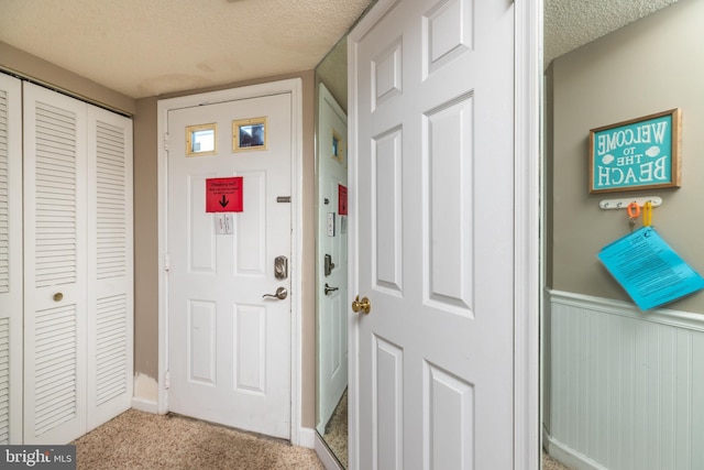 foyer with a textured ceiling and light carpet