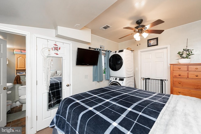 bedroom featuring ensuite bath, ceiling fan, and stacked washer and dryer