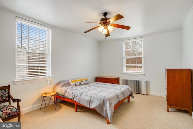 bedroom featuring ceiling fan, multiple windows, radiator, and light carpet