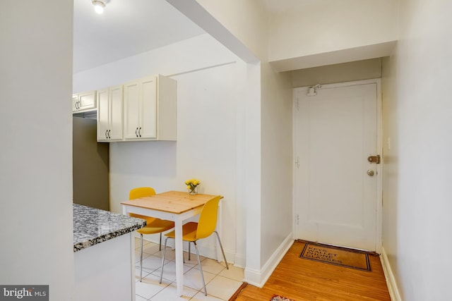 kitchen featuring light wood-type flooring, white cabinetry, and dark stone countertops