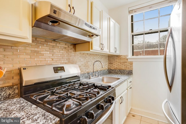 kitchen featuring sink, tasteful backsplash, light stone countertops, light tile patterned flooring, and stainless steel appliances