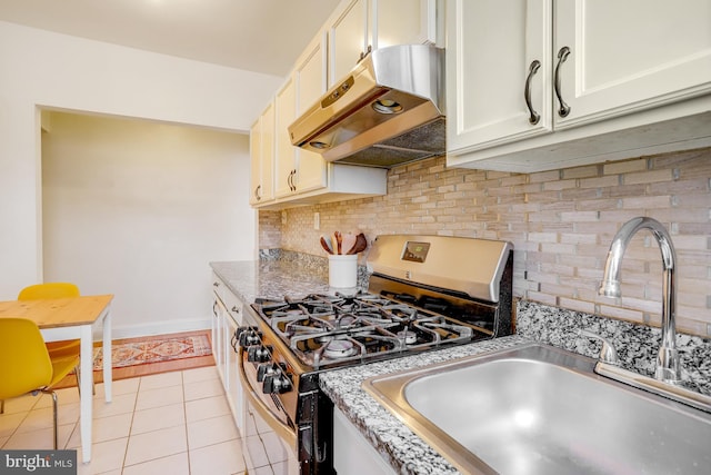 kitchen with sink, backsplash, light tile patterned floors, light stone counters, and gas stove