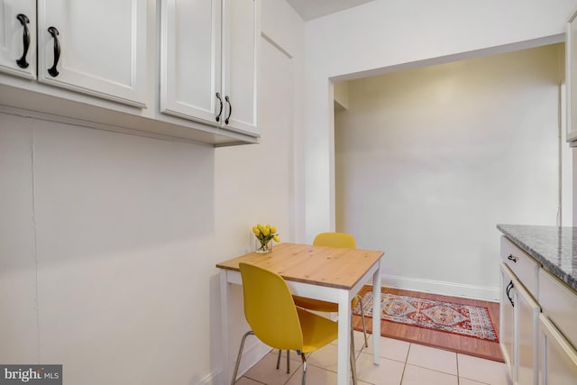 kitchen featuring light stone countertops, white cabinetry, and light tile patterned floors