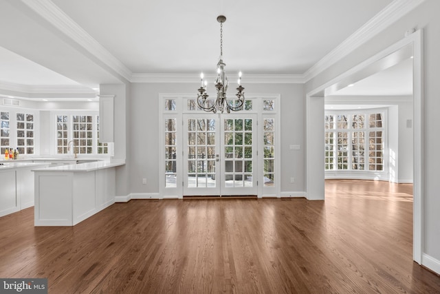 unfurnished dining area featuring crown molding, dark hardwood / wood-style floors, and a notable chandelier