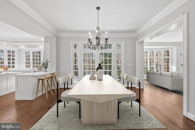 dining area featuring an inviting chandelier, ornamental molding, and wood-type flooring