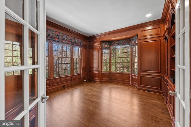 spare room featuring french doors, hardwood / wood-style floors, crown molding, and wood walls