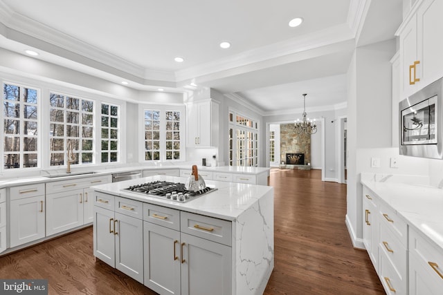 kitchen featuring white cabinetry, appliances with stainless steel finishes, a stone fireplace, and a kitchen island