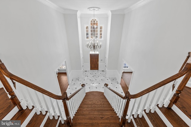 stairway with wood-type flooring, crown molding, and a chandelier