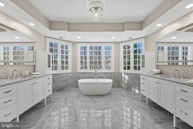 bathroom featuring tile walls, a tub to relax in, and vanity