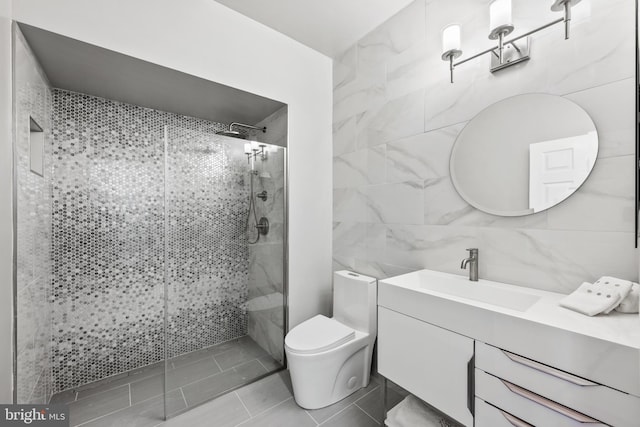 bathroom featuring toilet, a tile shower, tile walls, and vanity