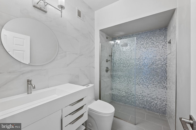 bathroom featuring toilet, vanity, tile walls, backsplash, and tiled shower