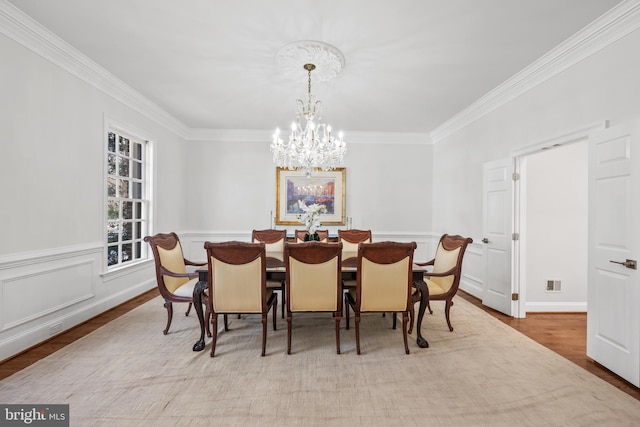 dining area with an inviting chandelier, ornamental molding, and light hardwood / wood-style floors