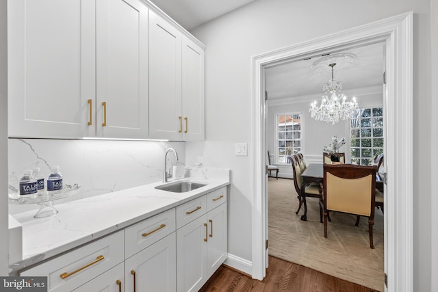 kitchen with decorative light fixtures, sink, dark wood-type flooring, white cabinets, and light stone counters