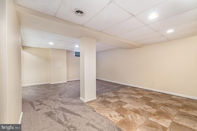 basement with a paneled ceiling and carpet flooring